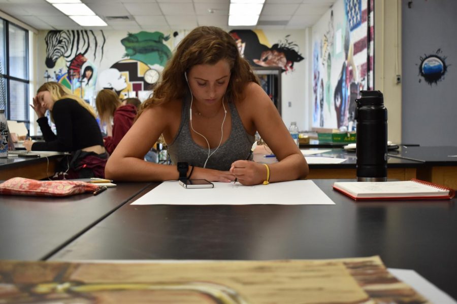 Junior Anna Butler listens to music as she works on a piece in her AP studio art class.