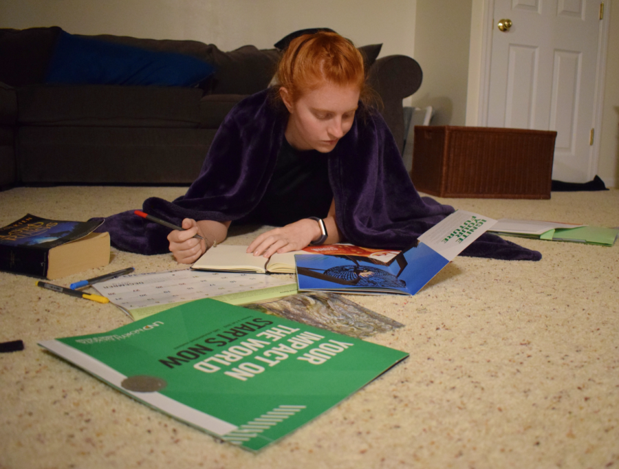 2019 alumna Nell Jaskowiak looks over college brochures, weighing the benefits and drawbacks of each school. Jaskowiak plans to attend a state school in the fall. “I feel like so many kids take college for granted,” Jaskowiak said. “I think kids don’t realize how amazing it is to pick good schools to apply for and have good choices to choose from.” 