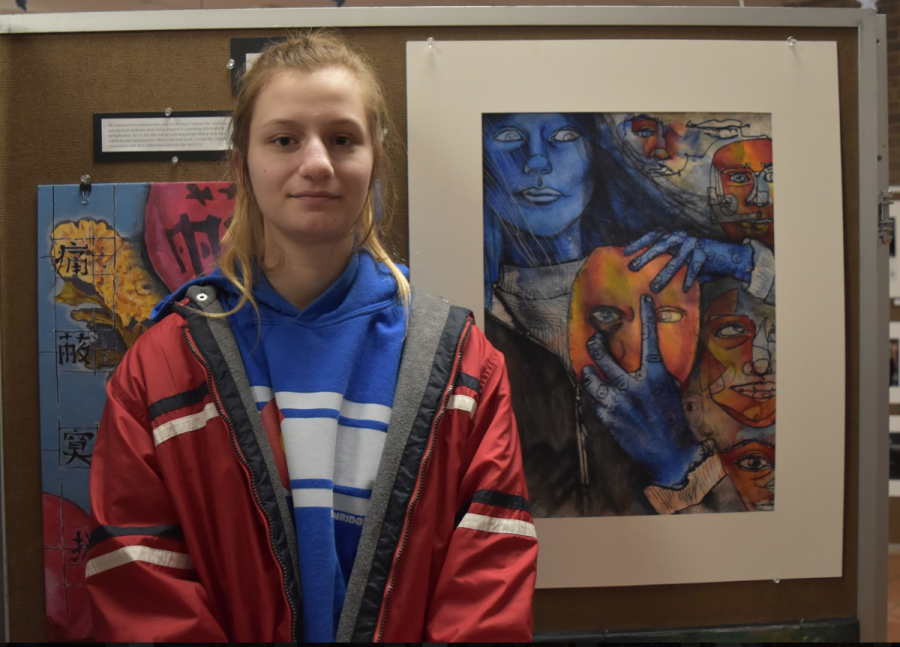 Art student of four years, senior Teya Everts stands in front of a collage of her paintings. Along with watercolor paint, she used colored pencil, strings and glue to create her pieces. “A lot of them are supposed to show people hiding their true emotions and themselves trying to get out of a darkness,” Everts said. “It’s supposed to be someone pulling off a mask. They pretend to be happy and show all these emotions but really are distraught.”