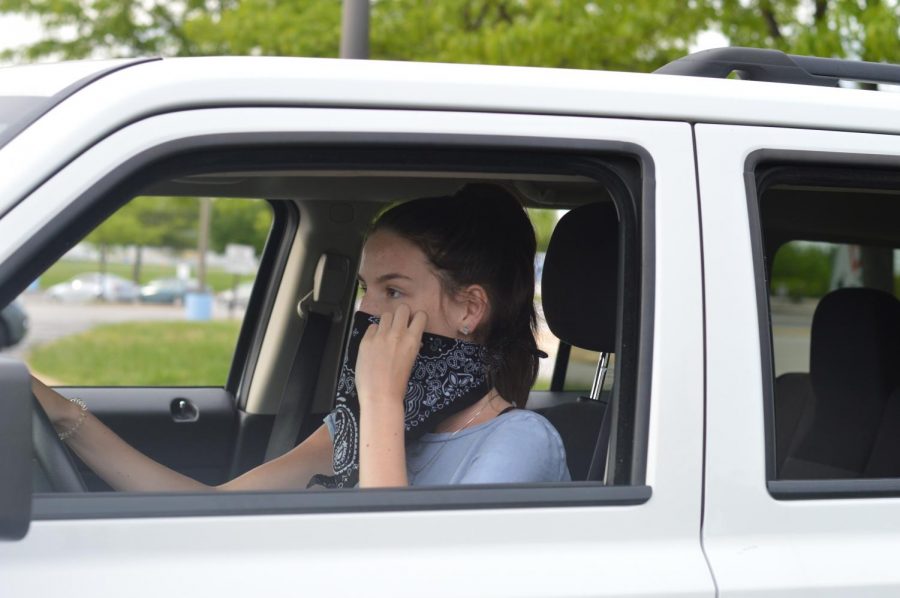 Using a bandana as a makeshift mask, sophomore Ellie Moriarity adjusts it on her face before she begins to drive. Moriarity believes there is always a risk associated with leaving your house during these uncertain times. “I think its important to wear a mask right now because there is no way of knowing if you have contracted the coronavirus,” Moriarity said. “Its better to be safe than sorry when it comes to protecting those around you.”
