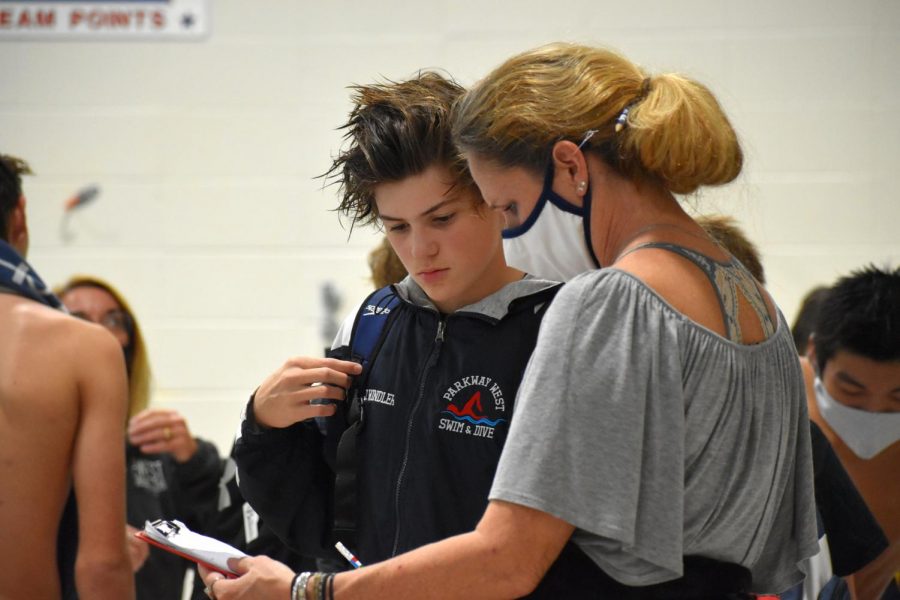 Conferencing with his coach after a meet, sophomore Jack Windler reflects on his performance from the previous event. Due to the many doubts about if there would even be a season, Windler felt grateful that he was able to swim for his school. “Receiving the news from MSHSAA that there would be a season was relieving,” Windler said. “This year really gave me a chance to reconnect with the team [as]  a whole.” 