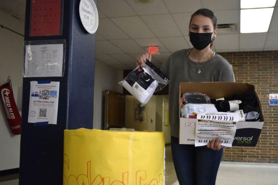Senior Ashleigh Morelli holds a box filled with socks the German club collected through their Socktoberfest event. “If I was in that situation, I would want someone to help me. I don’t think it is fair that people turn their shoulders and shun them for not being able to provide for themselves,” Morelli said.