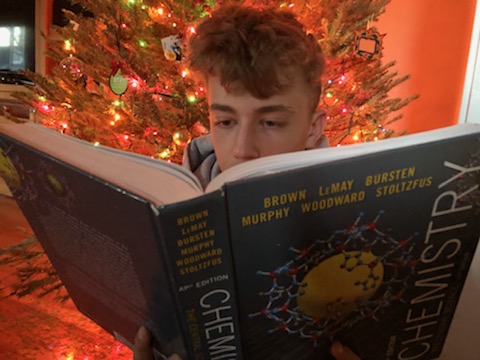 Junior Zachary Schade sits in front of his family christmas tree while studying for finals. Schade thought that having finals after winter break caused unnecessary stress which makes it harder to enjoy the holidays. “I think finals after break forces students to study instead of enjoying what should be time with their family [away] from school,” Schade said. “It places an unpleasant cloud over the holiday experience and doesn’t allow a break before the start of a new semester.”