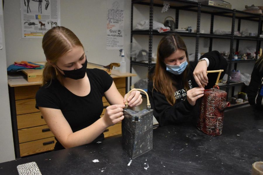 Junior Darcie Morgan and senior Annie Zahoran work on teapots in their Ceramics II class. The requirements for the project included the use of slabs and the creation of a linoleum stamp to make a functional teapot. “[When doing ceramics], you have an original idea in your head, and then [when] you try it out, and it doesnt work out, you have to go back and revise,” Morgan said. “Originally, I was going to have different plugs on the teapot, but then I realized I didnt go with my design, so I changed it so itd be more geometric.” 
