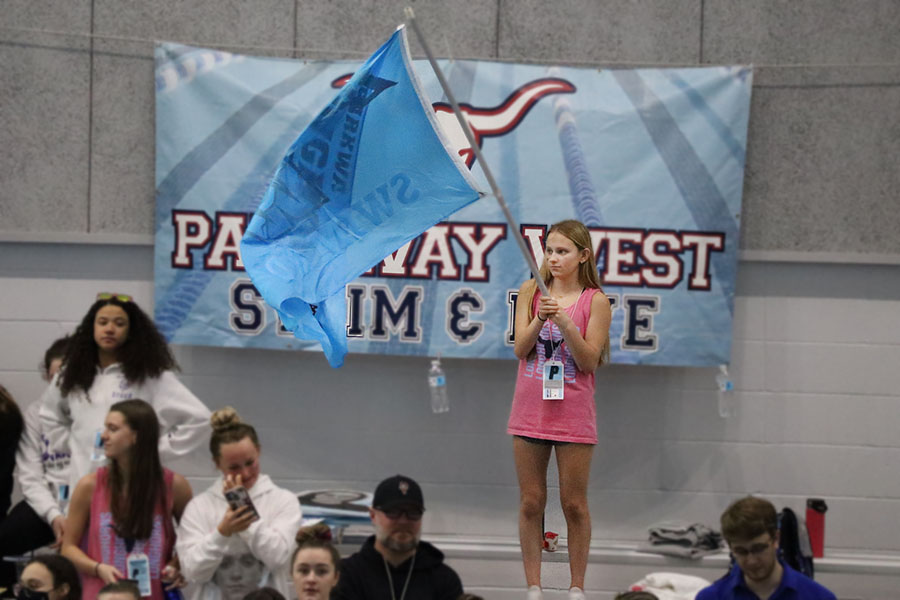 Supporting her team from the sidelines at the 47th Annual Girls State Meet on Feb. 18, sophomore Alli VanValkenburgh holds the swim and dive flag proudly in the air. The team won the 400 free relay, securing 1st place in the state. “I was super proud,” VanValkenburgh said. “My sister [Megan] had just swam the last event of her high school career and it was [beyond] fun to watch. It has [also] been super fun watching everyone improve and grow this season.”
