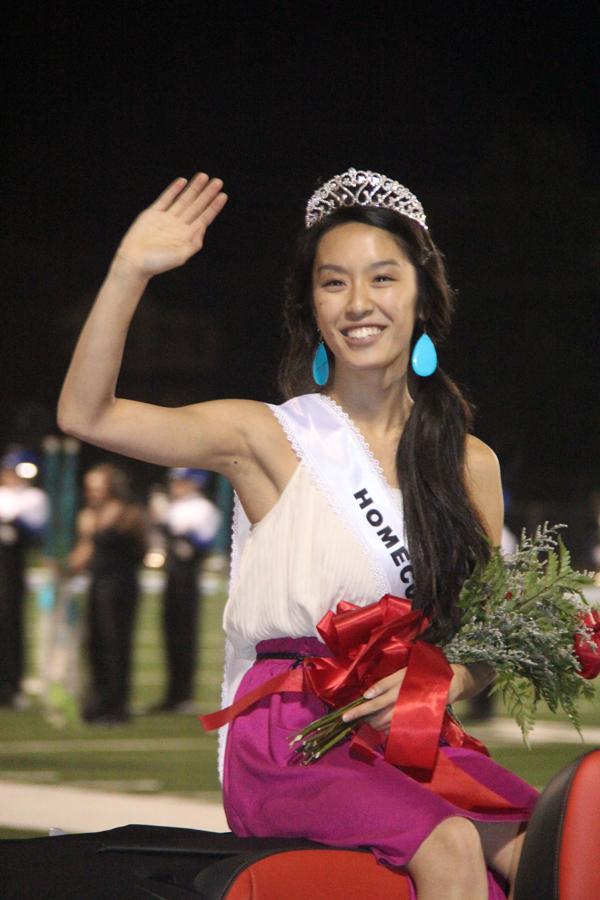 During half time at the Homecoming Football game, senior Homecoming Queen Yvette Lu waves to the crowd. Lu was voted as queen by the student body via Infinite Campus.