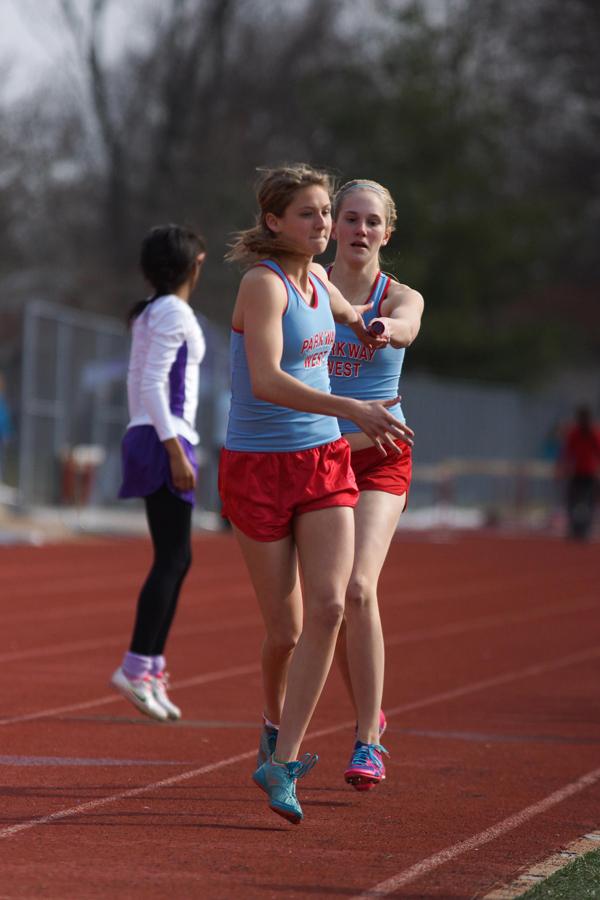 Entering the exchange zone, freshman Rachel Osborne hands off the baton to sophomore Maddie Brown, after finishing her leg of the 4 by 800 meter relay. The team competed in the Parkway Quad at South on March 28, placing first in the event with a time of 10 minutes, 39 seconds.
