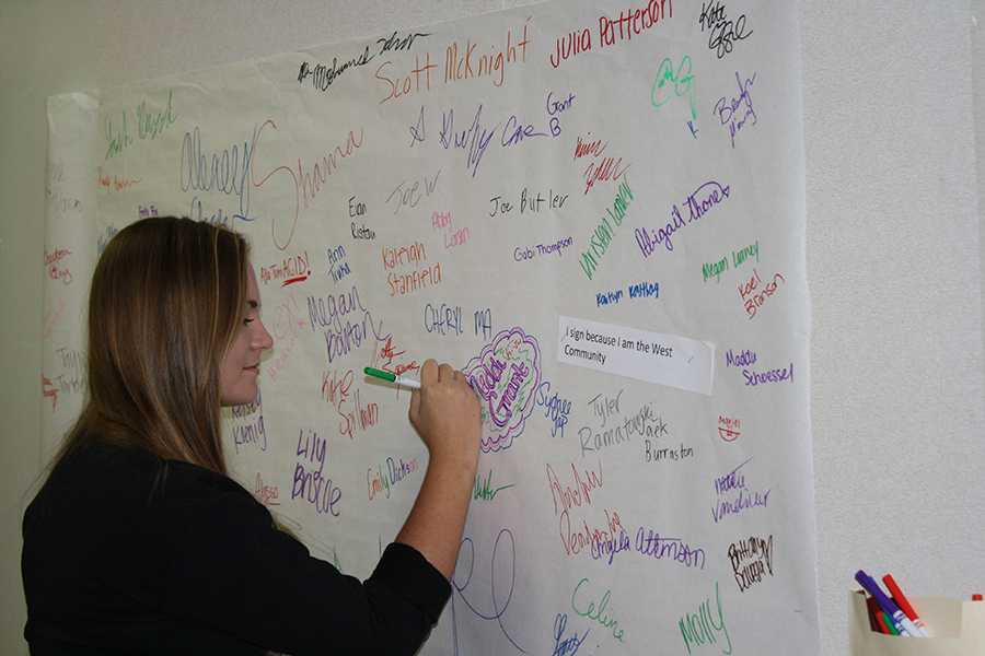 Freshman Katie English signs a poster in front of Mrs. Kerpashs room pledging to be color brave.