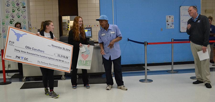 During first lunch, juniors Emily Wind and Shannon Anderson give Custodian Ollie Caruthers a check for 33K.
