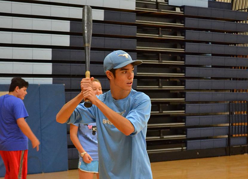 Sophomore baseball player Alex Constantin works on his hitting skills in his physical education class, focusing on making contact with the ball.