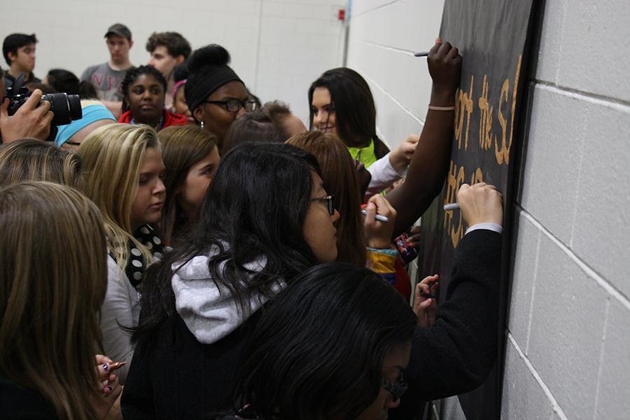 Students sign a poster stating, I support the Social Justice Protest after student-led walkout.