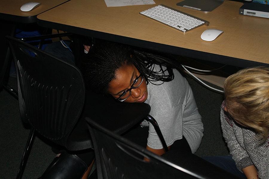 Following the Intruder Drill procedure, junior Vericia Pearson hides underneath the desk.