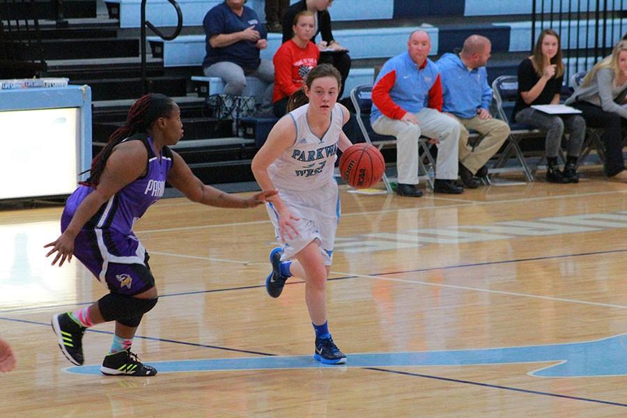 Dribbling the ball down the court, senior Lee McMullin defends the ball from Parkway North.