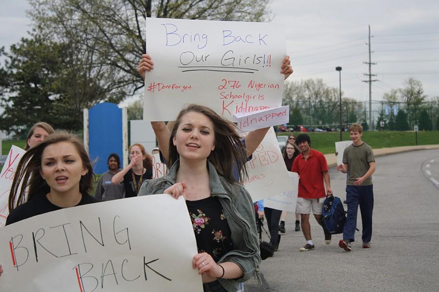 Junior Sidney Baker and sophomore Stephanie Sanders hold a poster in the march. Students chanted phrases like Its been one year, one year no change, bring back our girls and How many? Two hundred seventy six!