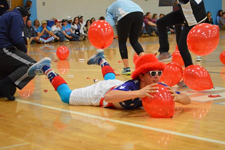 Junior Alex Karrenbrock lays on a balloon to get it to pop in order to win the competition to spell PWEST first. 