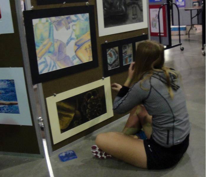 Junior Kendall Welch sets up her board at the district art show