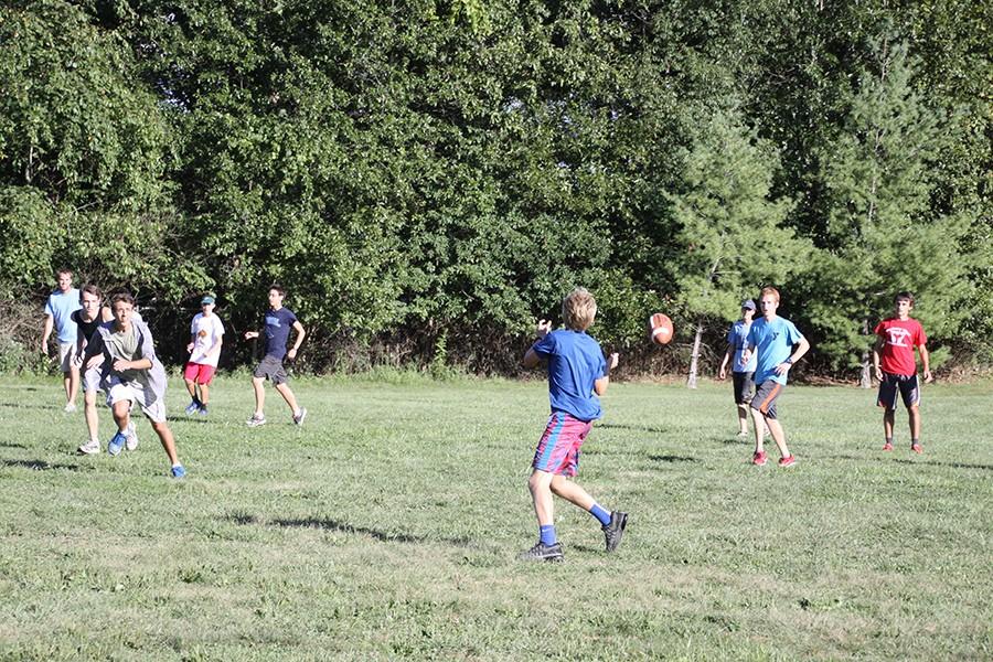 Junior Grant Aden completes a pass to sophomore Blake Selm in a game of touch football. At 4:30 p.m., the team reconviened at Ferris Park in Ballwin to have a picnic and spend time together.