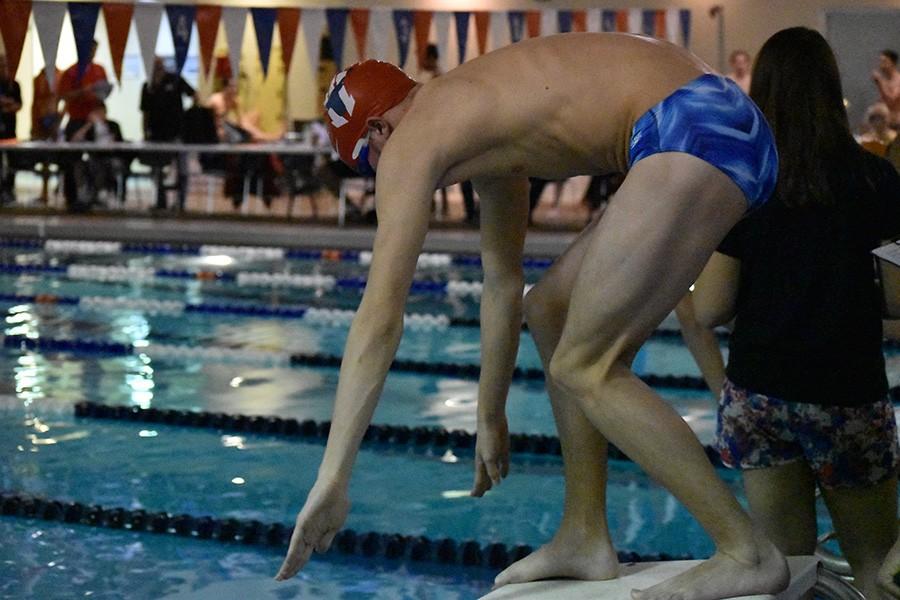 Crouching to meet the starting block, freshmen Tim McAuliffe prepares to leap into the water. The team won first at the Suburban Central Conference Meet.