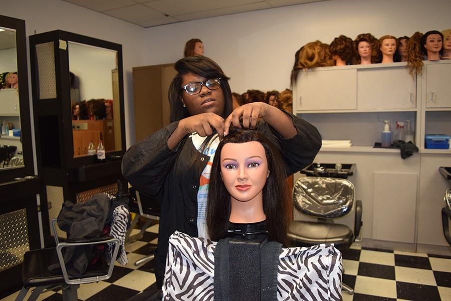 Working on a mannequin head of hair, junior Jasmine Black attends cosmetology class. 