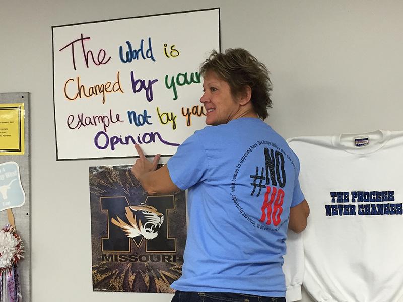 Wearing a Vivian Edwards #NoH8 shirt, Math Teacher Susan Dean hangs motivational posters in her room to encourage students to treat others with respect.