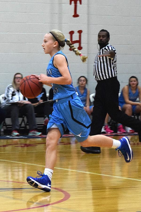 Dribbling down the court, freshman Tess Allgeyer looks for a player to make a pass.