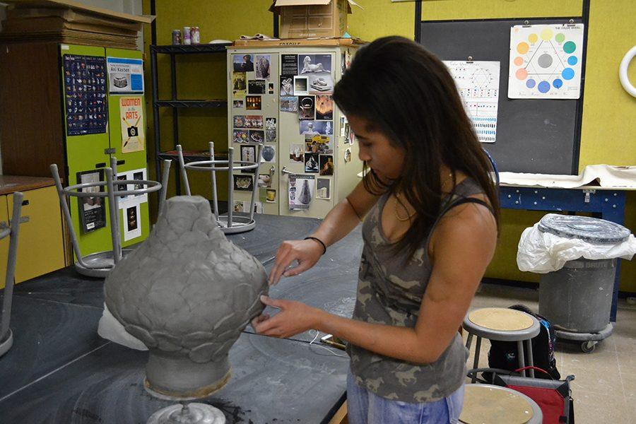 Junior Mia Walton puts the final touches on her coil pot during a Clay Club meeting. Since the August, Clay Club has been meeting in Ceramics teacher Ashley  Drissel’s room in the pursuit of creating art. “I joined because I saw how much fun playing with clay in class was and I wanted to come up with other projects,” Walton said. “My coil pot took four weeks, from carving out scales to creating the coils, but it was definitely worth it, the pot turned out great.”