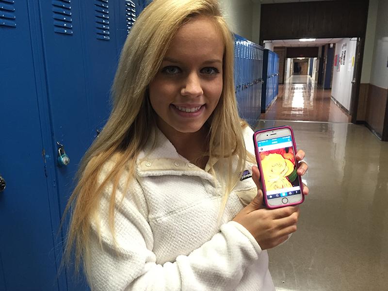 Olivia Daiker poses with her account open on her phone.