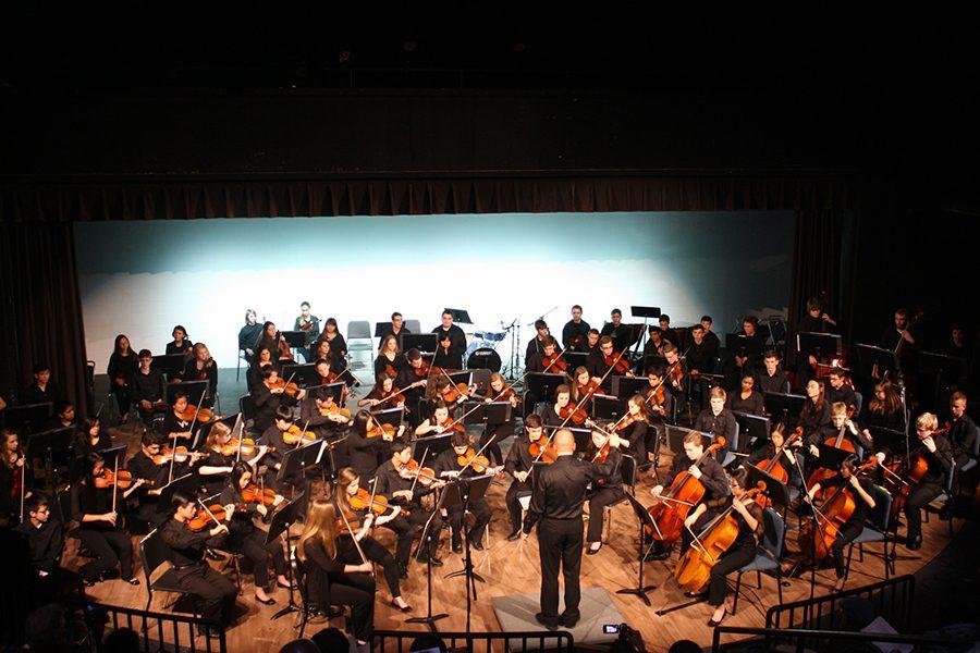 Directing+the+orchestra+at+in+the+theater%2C+Mr.+Sandheinrich+waves+his+arms+to+conduct+his+students.