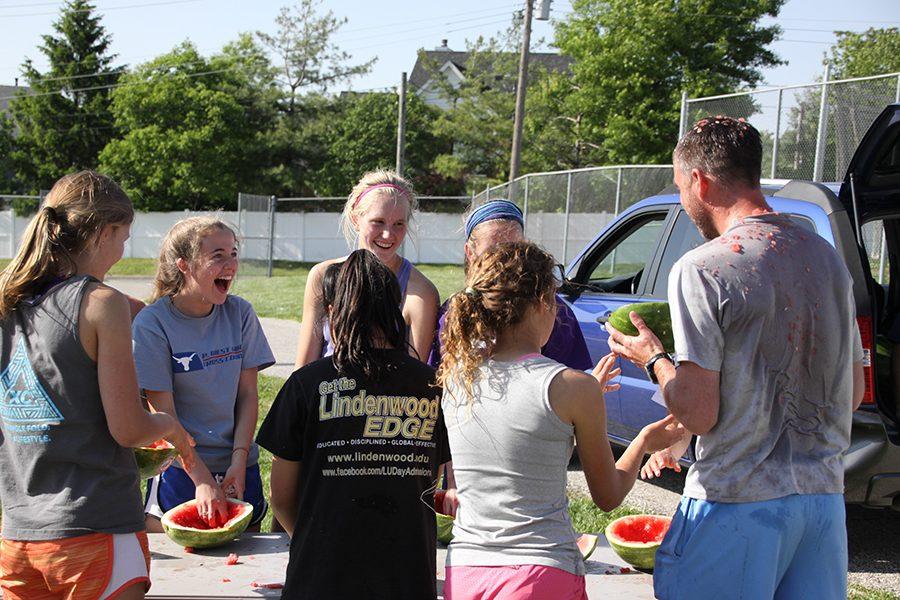 Cleaning out their watermelon helmets,  freshman Claire Smout, sophomore Betsy Wait, juniors Maggie Hulen and Maggie Morse, seniors Rachel Osborne, and Abby Allgeyer, and Coach Kevin John, prepare to put the melon shells on their heads. “I was one of the first people to transform their watermelon into a watermelon hat,” Osborne said. Osborne drove home wearing the watermelon hat that evening.