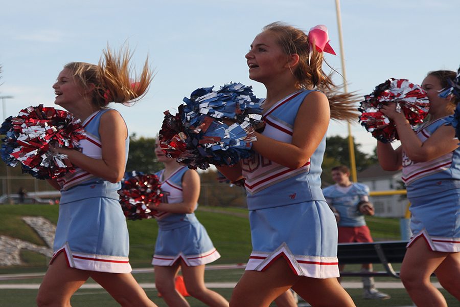 Rallying the crowd, competition cheerleaders freshmen Kelsey Long, Lauren Adam and Sophie Gulino support the football team with the JV team.
