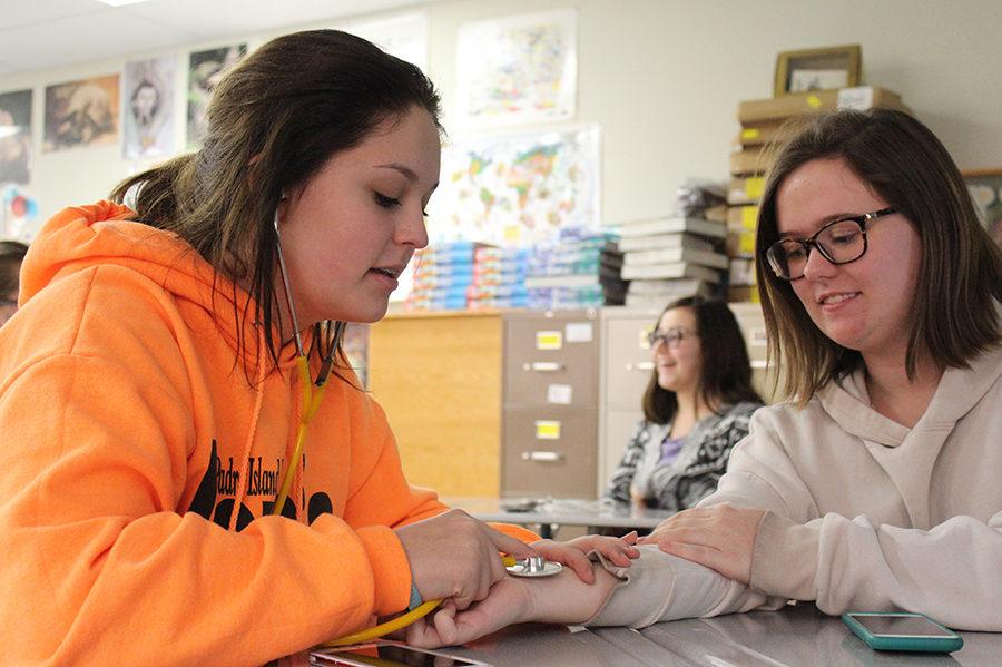 Sophomore Emily Sexton uses a stethoscope to measure sophomore Clair Osterhaus’s heart beat. 
