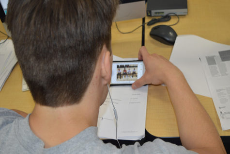 With headphones in, student watches a YouTube video in class. A study by the University of Nebraska estimates that students spend up to 20 percent of class time on phones.