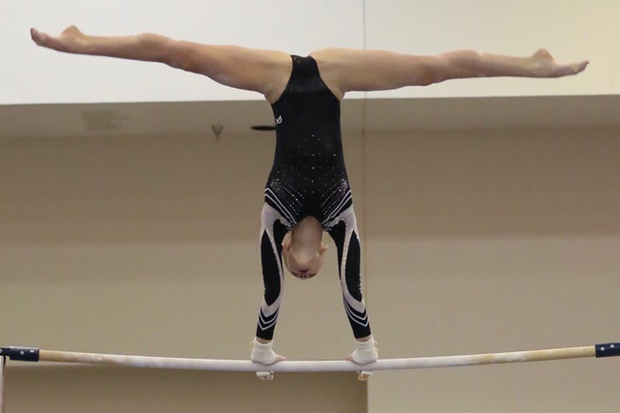Sophomore Abby Socha does a cast handstand on bars at the World Class meet.