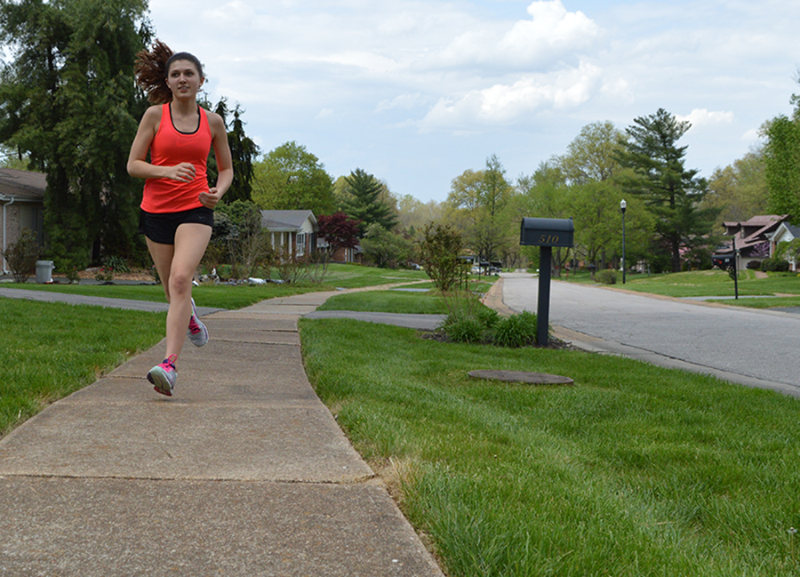 Running down the street, freshman Emma Caplinger trains for upcoming cross country summer camps.