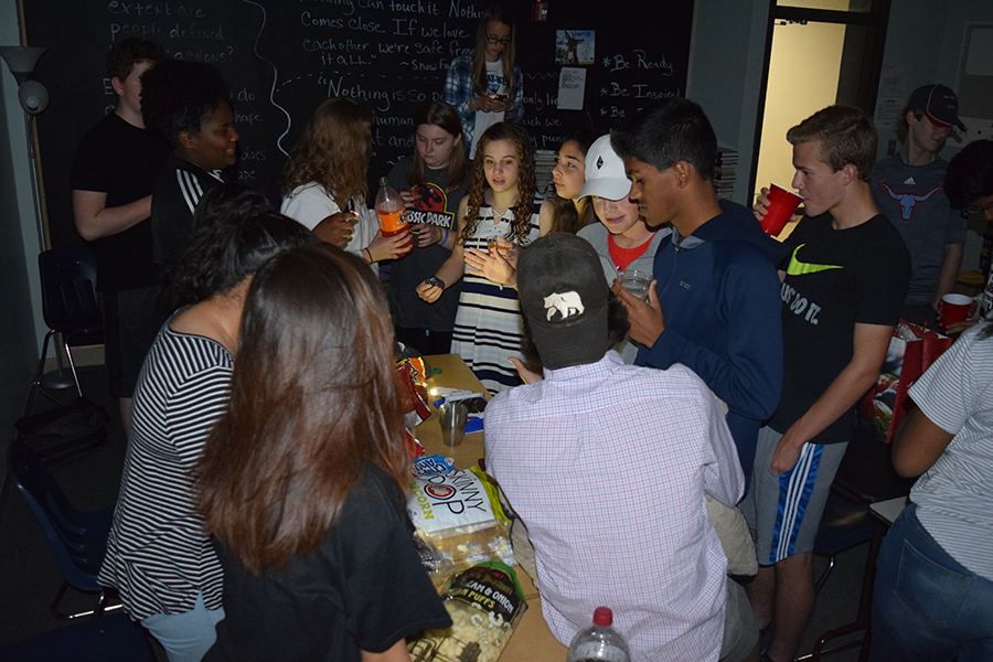 Students crowd around a table full of food as an end of the year reward.  