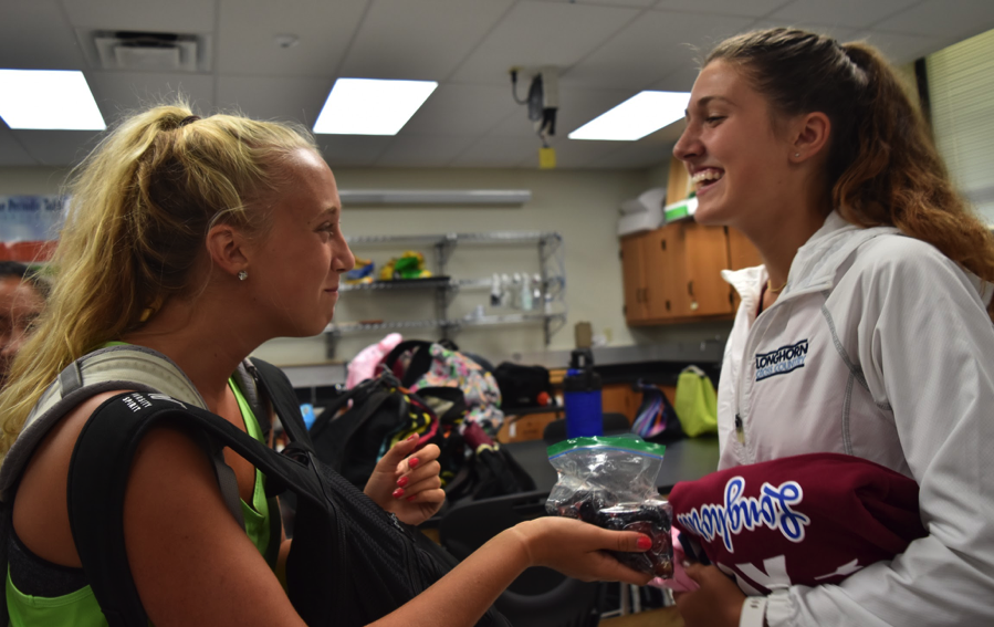 Sharing grapes in cross country coach Charles Cutelli’s room before practice, junior Sophie Pellegrino and sophomore Emma Caplinger chat about their day.