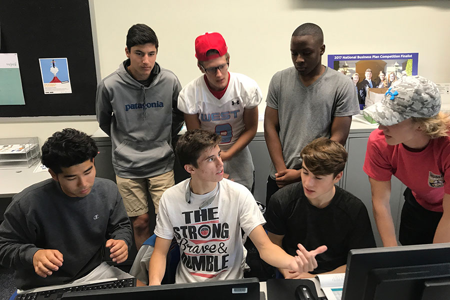 Gathered around a computer, the Global Goodies finance team prepares to register their business through Virtual Enterprise.