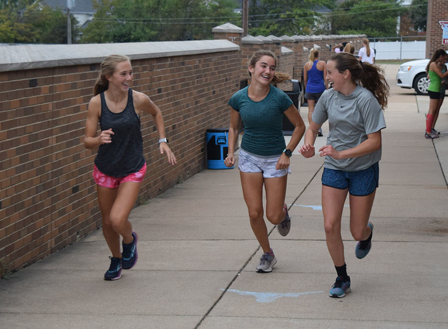 Laughing, freshman Leah Selm, sophomore Chloe Hershenow and freshman Anna Butler start out on an easy road run.