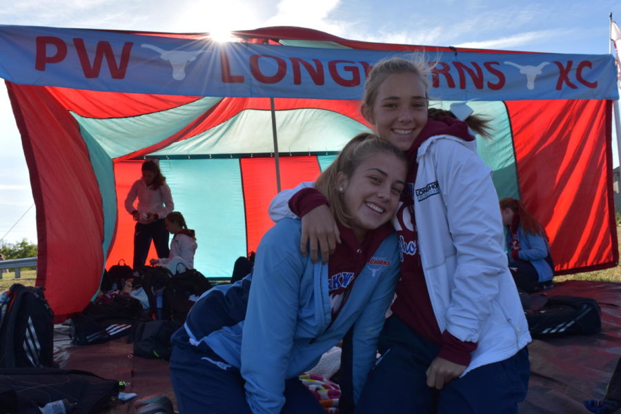 With light shining through the team's red and blue tent, freshman Leah Selm and senior Hannah Roth huddle up on a chilly morning at the West Invitational. 