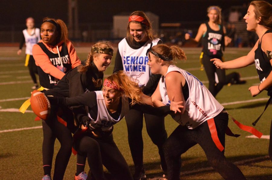 Running from the juniors, senior Emma Moss tries to prevent her flag from being pulled. Moss tried to score a touchdown during the annual Powder Puff game. Everyone started to tug at my flag which caused my shoe to fall off! The play stopped because of that, Moss said.