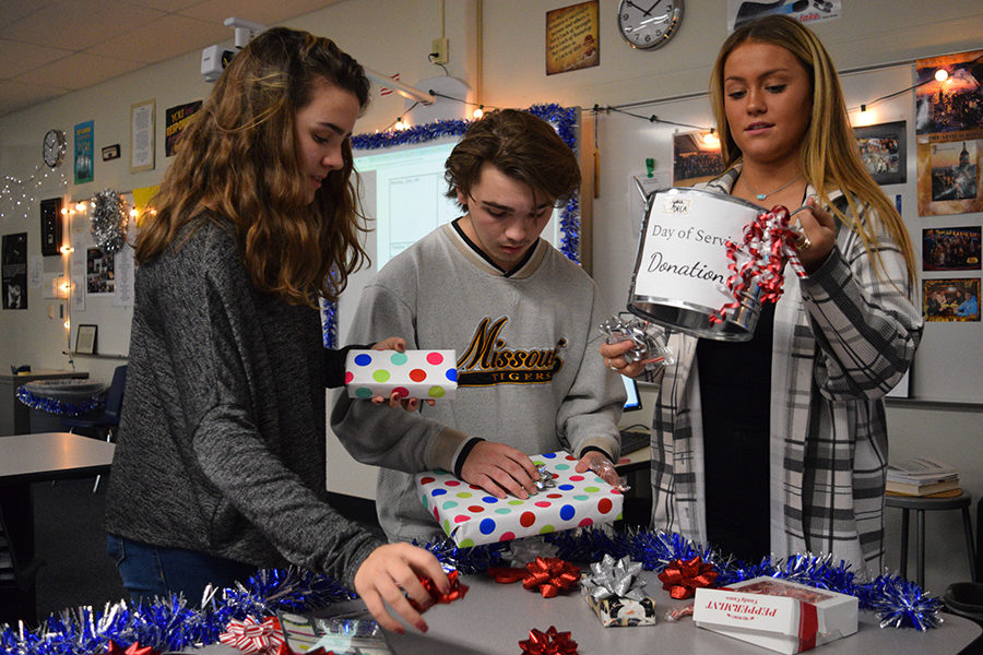 Wrapping gifts and organizing supplies, sophomore Rachel Deadwyler, junior Johnathan Stephens and senior Brandi Beaubien set up for Marketing II's holiday wrapping event. Community members have the opportunity to bring the gifts for marketing and DECA students to wrap in exchange for a donation to the Day of Service programming. "For parents who are really busy this time of year, it's really helpful for them to just be able to drop off gifts. It relieves a lot of stress and it's for a really good cause," Beaubien said. 
