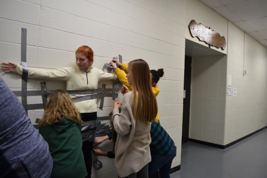 Section editor Nell Jaskowiak gets duct-taped to the wall in a ‘trial run’ for the fundraiser being put on by the editorial staff in which teachers will be being duct taped. The fundraiser will be held in the cafeteria with donations to the teacher you want duct taped being accepted starting Jan. 22. “There was a second when they pulled the box out from under [my feet] and I wondered what the heck I was doing,” Jaskowiak said. “But sure enough, I stuck.”