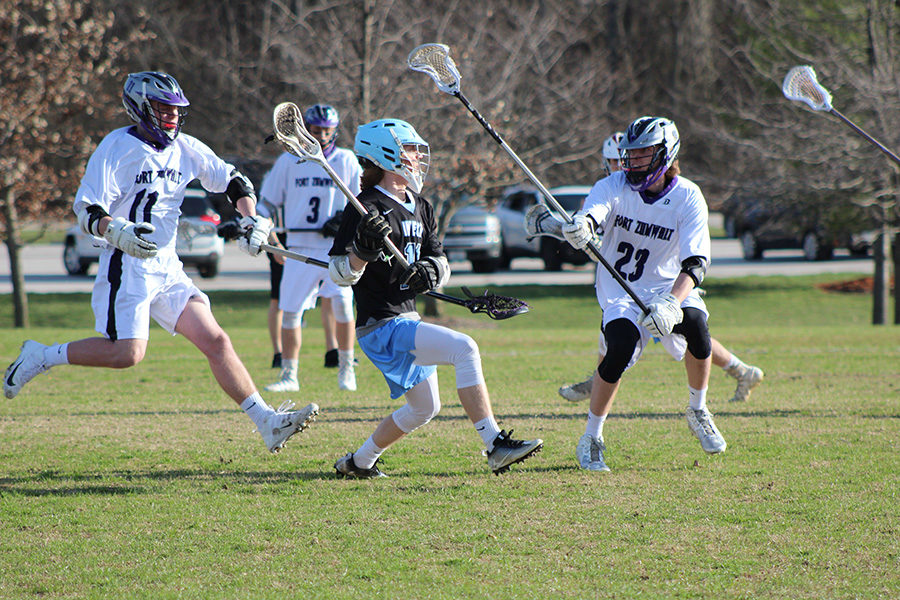 Junior Luke Griffith dodges defenders and passes the ball during a varsity lacrosse game April 5 against Fort Zumwalt West. West took the lead early on and won 14-2. It was our first game [after spring break] so it was good to shake off the rust. Close to the end of the game I assisted [junior] Michael Imral; it was his first goal of the season, I was proud of him, Griffith said. 