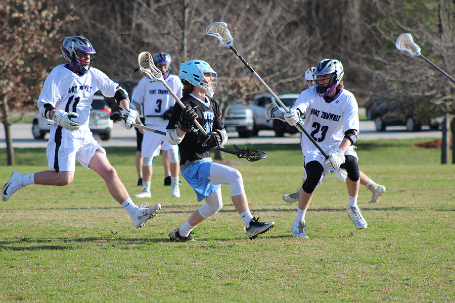 Junior Luke Griffith dodges defenders and passes the ball during a varsity lacrosse game April 5 against Fort Zumwalt West. West took the lead early on and won 14-2.
