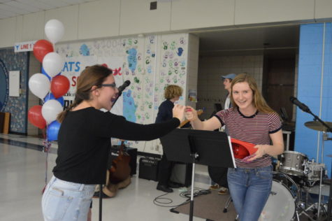 Junior Harper Stewart hands junior Caroline Dunn a raffle prize, a Menchies gift card. “[The] Puerto Rico [concert] took a lot of long hours, tears and hard work, and having someone else recognize that fact and congratulate us for it outside of the West community was incredibly humbling,” Stewart said. “It reminded me of how all that work was funneled into a project that did so much good, whether that be the money we raised or the awareness we brought to the West community specifically about Puerto Rico and their struggles”
