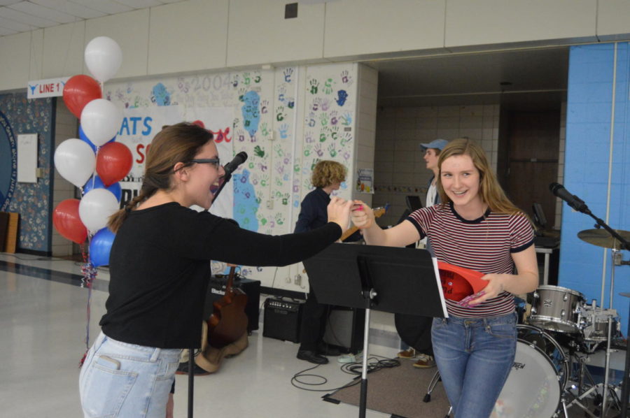 Junior Harper Stewart hands junior Caroline Dunn a raffle prize, a Menchie's gift card. “[The] Puerto Rico [concert] took a lot of long hours, tears and hard work, and having someone else recognize that fact and congratulate us for it outside of the West community was incredibly humbling,” Stewart said. “It reminded me of how all that work was funneled into a project that did so much good, whether that be the money we raised or the awareness we brought to the West community specifically about Puerto Rico and their struggles”
