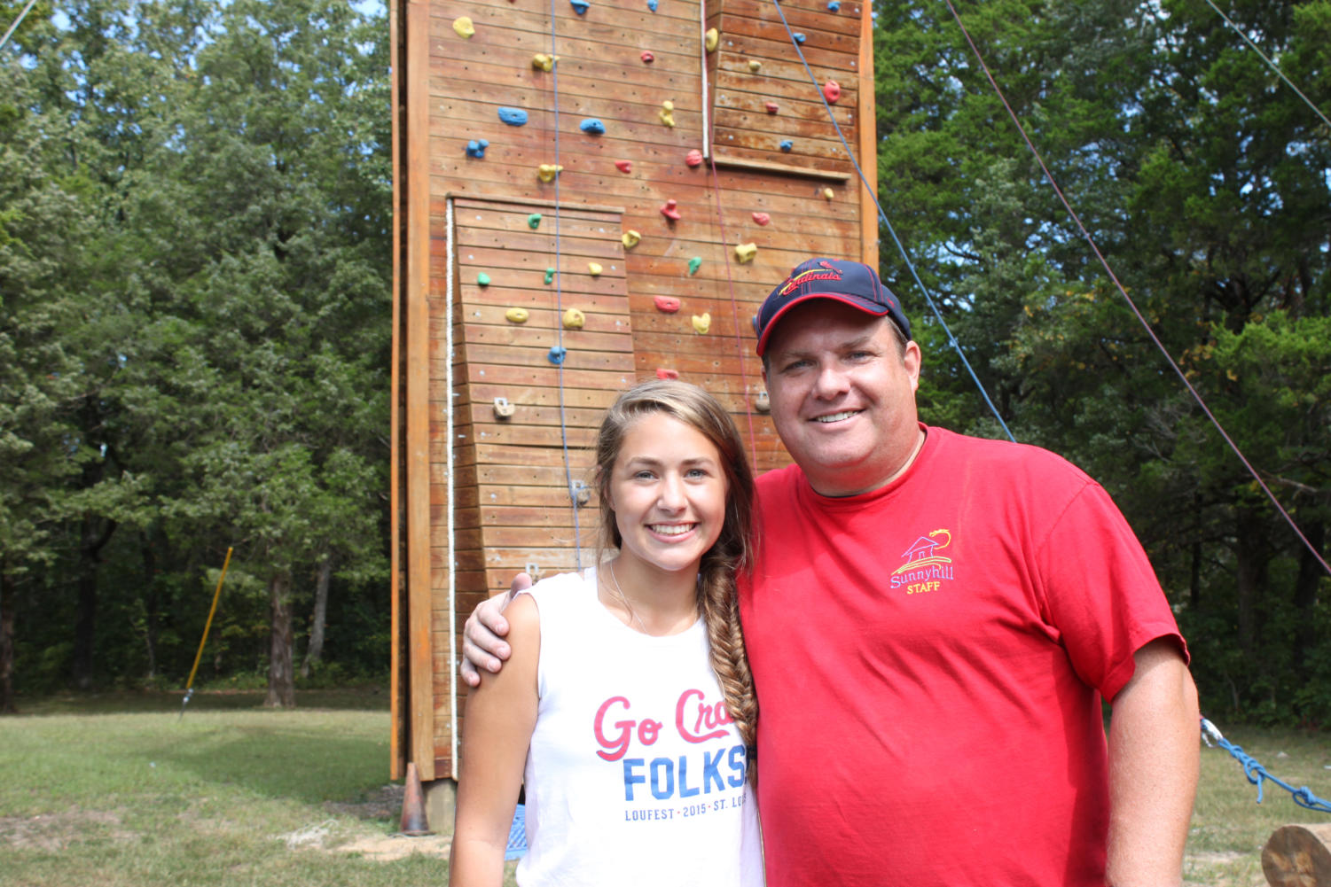 Posing with camp director Rob Darroch, senior Emily Rayfield stands in front of the climbing tower. Rayfield had been going to Sunnyhill Adventures since she was 7.