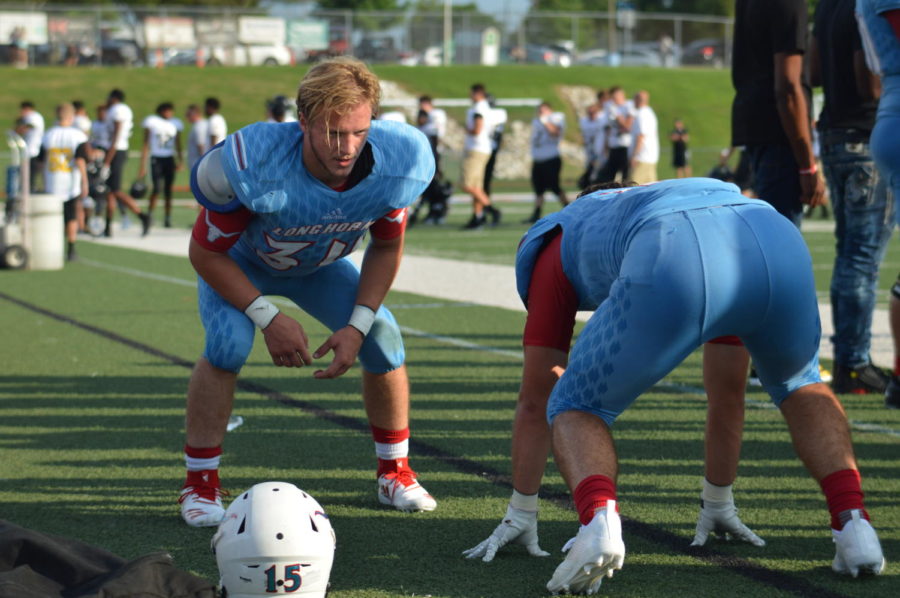 Preparing for the scrimmage to begin, junior middle linebacker Luke Ward helps junior defensive lineman Tommy Mohan practice his defensive skills during Red and Blue Night. The varsity team started off their season with the jamboree, where they competed against Fort Zumwalt, St. Charles and Westminster. “The scrimmages are always fun. The first scrimmage felt rough, and like we were too slow, but by the third, I think the rust and butterflies were knocked off, and the team looked good,” Ward said. “Sportsmanship was high, and we got out with no significant injuries. Overall, it was a great way to kickoff the season.”