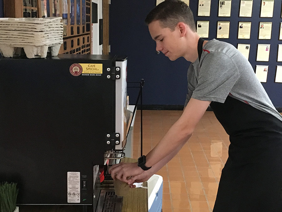 Using the latte machine, Blue Brew crew member and junior Pierce Burns prepares an order for a customer. The crew members and Marketing II students are learning from and adapting to the wants of the students. “Some people may have noticed our new straws. We wanted to get away from Community [Coffee’s] straws and use paper ones, which was a request, because it is more environmentally friendly,” Burns said. 

