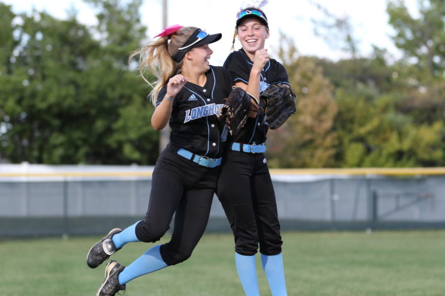 Rallying together during a home game Oct. 8, senior Alexa Abney and sophomore Emma Breidecker shoulder bump at the start of the varsity softball game against Ladue High School. Throughout the season, the varsity team mentally prepared in between innings by hyping up their fellow teammates. “Usually before every inning the infielders ran around and high fived each other before the batter came out,” Abney said. “Us outfielders always got together and shoulder bumped or chest bumped.”